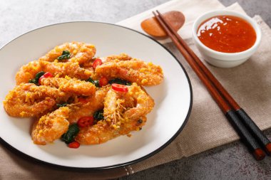 Asya usulü kızarmış karides, tuzlu yumurta sarısı, köri yaprakları ve biber sosu ile servis edilen yakın plan tabakta. Yatay