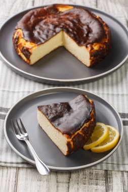 Masanın üzerinde limon dilimleri olan dilimlenmiş kremalı, yanık basklı peynirli kek. Dikey