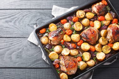 İtalyan barbekü balzamik tavuğu, patatesli, kırmızı soğanlı ve domatesli ahşap bir masada yakın plan. Yukarıdan yatay üst görünüm