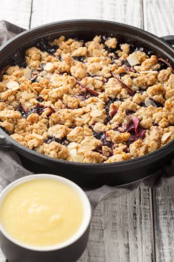 Ev yapımı vanilya soslu İsveç Fruit Crumble Pie Smulpaj 'ı ahşap masaya yakın plan. Dikey