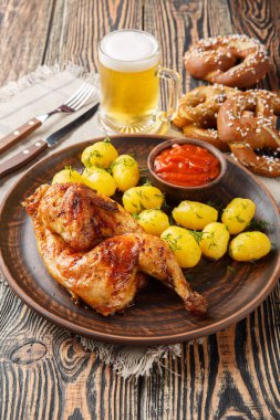 Oktoberfest Kızartma Tavuğu Withe Hendl yanında patates ve bira ile ahşap masada yakın plan kraker servis edilir. Dikey