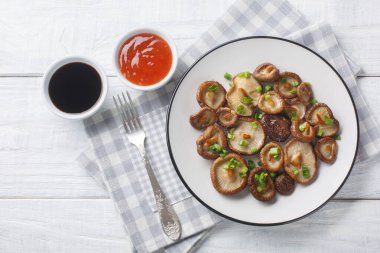 Kızarmış shiitake mantarı, yakın plan yeşil soğan ve ahşap masada baharatlı soslar. Yukarıdan yatay üst görünüm