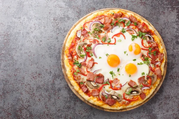 stock image Crispy Aussie pizza with bacon, eggs, peppers, mushrooms, mozzarella and red onions close-up on a wooden board on the table. Horizontal top view from abov