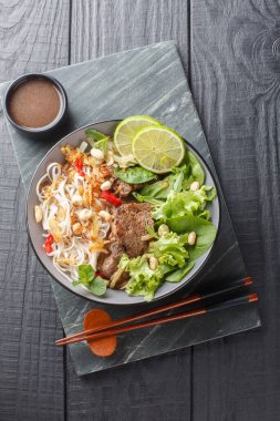 Pho tron ya da karışık pho klasik bir Vietnam yemeğidir. Et, erişte ve yeşillik içeren bir salata. Ahşap tabakta yakın plan. Yukarıdan dikey üst görünüm