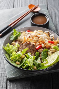 Vietnam bifteği, salata, Pho Tron, ahşap masadaki tabağa yakın çekim. Dikey