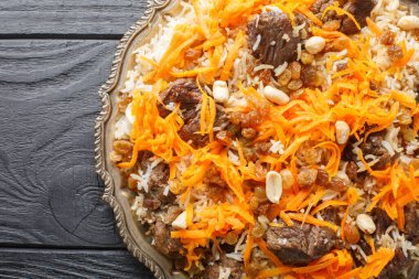 Afgan ulusal yemeği Kabuli Pulao pirinç pilavı kuzu, kuru üzüm, havuç, fındık, ahşap masadaki tabağa yakın baharatlar. Yukarıdan yatay üst görünüm