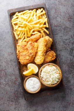 Fast food kızarmış balık, lahana salatası, patates kızartması ve ahşap tepside tartar sosuyla servis edilir. Yukarıdan dikey üst görünüm