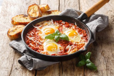 Purgatory 'deki sağlıklı İtalyan Shakshuka yumurtaları ahşap masadaki tavaya yakın plan. Yatay