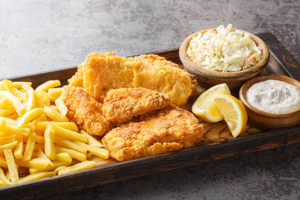 Tasty Fish Fry with coleslaw, French fries, tartar sauce and lemon closeup on the wooden board on the table. Horizonta