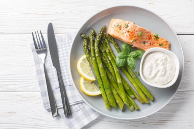 Çıtır kuşkonmaz ile nefis pişmiş somon. Masada tartar sosu ile servis ediliyor. Yukarıdan yatay üst vew