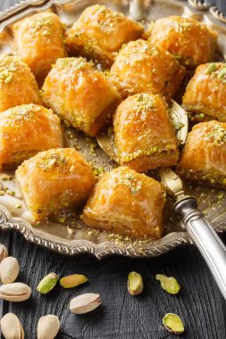 Geleneksel Orta Doğu Lezzetleri Pistachio baklava ya da ahşap masadaki tabağa yakın fistikli baklava. Dikey