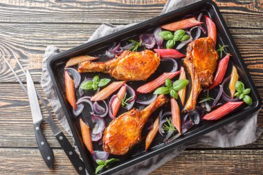 Kurutulmuş domuz pirzolası, kırmızı soğan, otlar ve bal jöleli ravent. Masanın üzerindeki fırın tepsisine yakın plan. Yukarıdan yatay üst görünüm