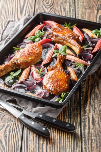 Pişmiş ballı domuz pirzolası, kırmızı soğan ve fırında pişirme tepsisiyle yakın plan. Dikey