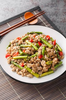 Asya yemeği stili kızarmış kuşkonmaz kıyma ve kırmızı biber tabağın üzerine yakın plan. Dikey