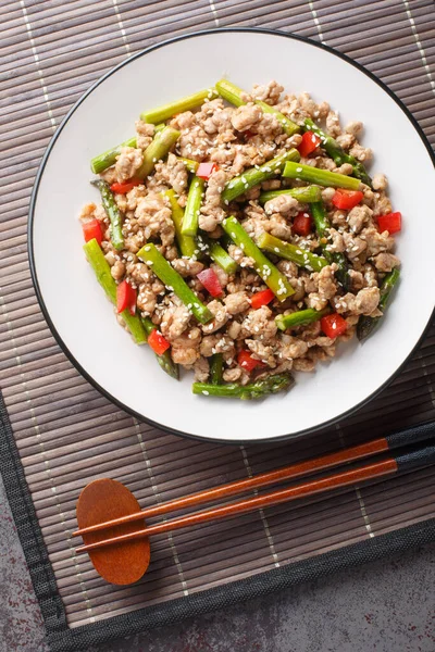 Asya yemeği stili kızarmış kuşkonmaz kıyma ve kırmızı biber tabağın üzerine yakın plan. Yukarıdan dikey üst görünüm