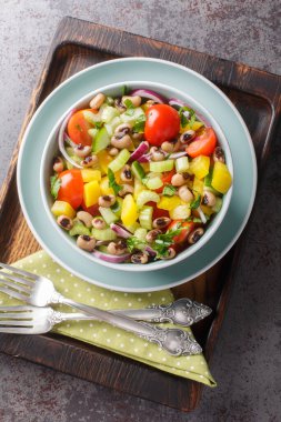 Domatesli salata, kereviz, salatalık, soğan, biber ve ahşap bir tahtanın üzerindeki bir kasede yakın plan kaynatılmış bezelye. Yukarıdan dikey üst görünüm