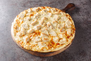 Masanın üzerindeki tahta tahtaya yakın plan parmesan kabuklu tavuk Alfredo Pizza. Yatay