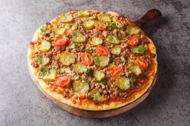 Lezzetli Pizza 'nın üstünde kremalı burger sosu, kıyma, peynir ve turşu var. Masanın üzerindeki tahta tahtaya yakın plan. Yatay