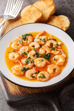 Gambas al Ajillo İspanyol usulü sarımsaklı karides tahtadaki tabağa yakın plan. Dikey
