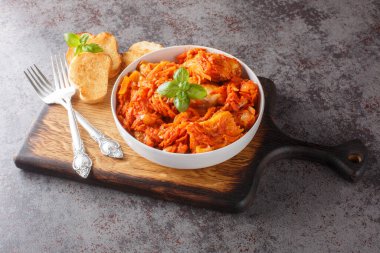 Baharatlı domates sosunda soğan ve havuçlu beyaz balık güveci. Masadaki tahta tahtada yakın plan tost ile servis ediliyor. yatay