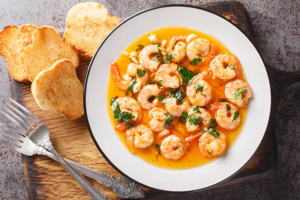 stock image Gambas al ajillo or garlic shrimp is a traditional Spanish tapas made by combining fresh shrimp with an ajillo sauce on the wooden board. Horizontal top view from abov