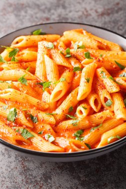 Masanın üzerindeki kaseye yakın çekimde, pembe domates soslu nefis bir makarna kasesi. Dikey