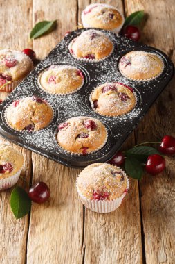 Masadaki muffin kalıbına yakın, kirazlı kekler ve pudra şekeri. Dikey
