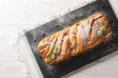 Lezzetli örülmüş çörek, çikolata ve krema. Masadaki tahtaya yakın plan. Yukarıdan yatay üst görünüm