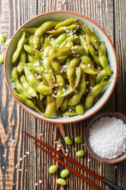 Masadaki tabağa yakın deniz tuzu ile tatlandırılmış Asya usulü kızarmış fasulye kabukları. Yukarıdan dikey üst görünüm