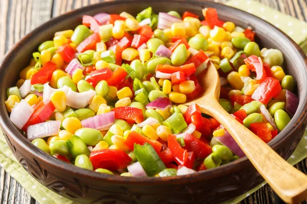 Delicious salad cooked with edamame soybeans, bell peppers, corn, tomatoes and onions close-up in a bowl on the table. Horizonta