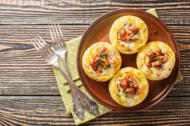 İçi domuz pastırması ve soğan dolu patates püresi dolu yakın plan bir tabakta masanın üzerinde. Yukarıdan yatay üst görünüm