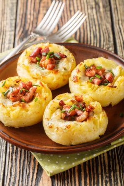 Pişmiş patates püresi yuvaları ve ahşap masadaki tabağa yakın domuz pastırması. Dikey