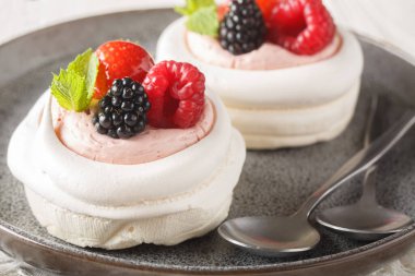 Ev yapımı mini kremalı Pavlova pastası. Böğürtlenli ve krem şantili. Ahşap masadaki tabakta. Yatay