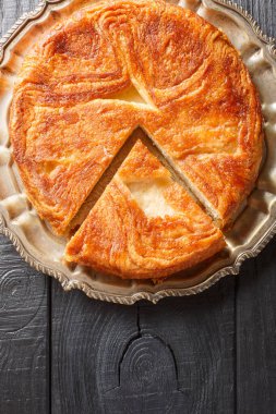 Kouign-amann. Masanın üzerindeki tabaktaki kaplamalı hamur kaplamasından yapılmış tatlı bir Breton keki. Yukarıdan dikey üst görünüm