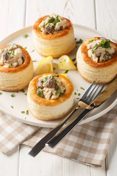 Tavuk, mantar ve krema ile doldurulmuş lezzetli börek vol-au-vent beyaz ahşap masadaki tabağa yakın. Dikey