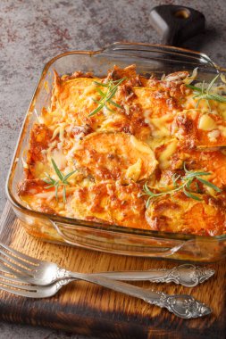 Çedar peynirli patates güveci ve biberiye yakın plan cam bir masa. Dikey