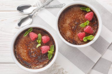 Masadaki ramekin içinde meyveli, çikolatalı, meyveli, meyveli, özel yapım brüle. Yukarıdan yatay üst görünüm