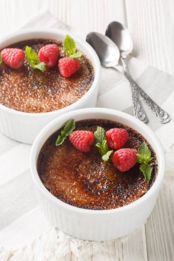Çikolata kremalı brüle karamelli, naneli ve ahudududulu, masanın üstünde ramekin var. Dikey