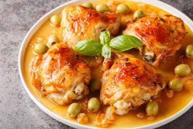 Masadaki tabakta yeşil zeytinlerle pişirilmiş kokulu tavuk butları. Yatay