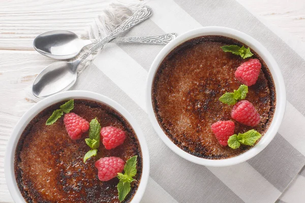 Geleneksel çikolata kremalı brüle tatlısı ve karamelli esmer şeker masanın üstünde ramekin. Yukarıdan yatay üst görünüm