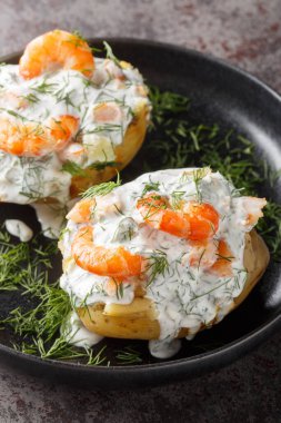 Ekşi kremalı fırında patates ve masaya yakın bir tabakta karides. Dikey