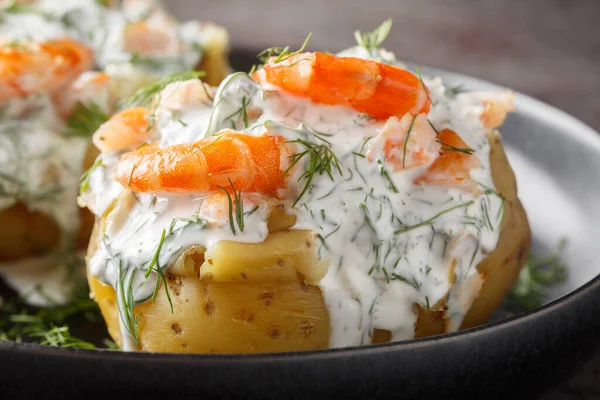Homemade jacket potatoes stuffed with sour cream sauce, dill and shrimp close-up in a plate on the table. Horizonta
