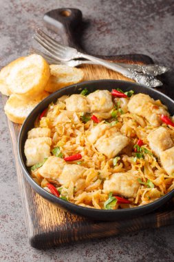 Masadaki tabakta lahana ve soğanlı beyaz balık filetosu. Dikey