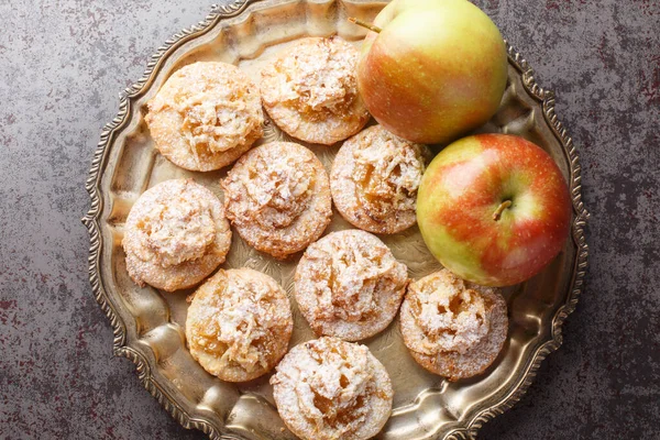 Cookies topped with apple jam and sprinkled with powdered sugar close-up in a plate on the table. Horizontal top vew from abov