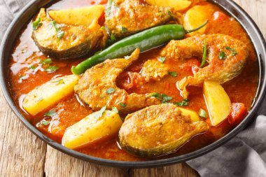 Lezzetli Asya balığı köri soslu, sarımsak, soğan rendelenmiş zencefil ve Hint baharatları ahşap masadaki tabağa yakın. Yatay