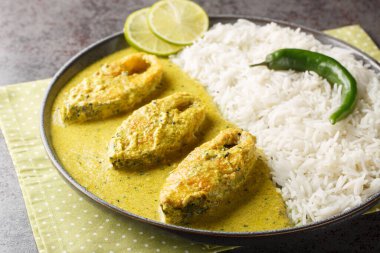 Bengali Shorshe Ilish ya da Hardal Sosu 'nda pişirilmiş Hilsa. Masanın üzerinde yakın plan beyaz pirinçle servis ediliyor. Yatay