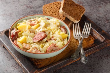 Patates, sosis, pastırma ve soğanla pişirilmiş lahana. Masanın üstünde yakın plan. Yatay