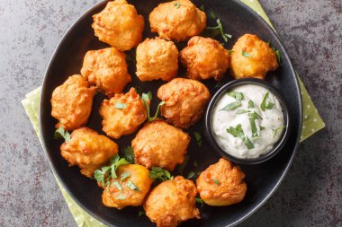 Susturucu köpek yavruları yumurta, soğan, kendi kendine yetişen un ve mısır unu ile yapılır, sonra da tabağın üzerinde çıtır çıtır ve altın kaplamasına kadar kızartılır. Yukarıdan yatay üst görünüm