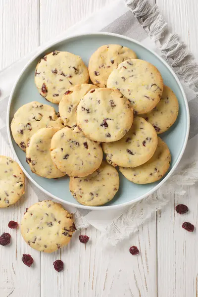 Cranberry Orange Shortbread Cookies are the perfect holiday cookie for the festive season closeup on the plate on the wooden table. Vertical top view from abov