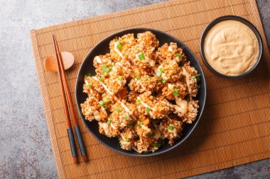 Bang Bang Chicken inanılmaz derecede çıtır çıtır tavuk ısırıkları serpiştirilmiş ve tabağın üzerine yakın plan sos serpiştirilmiş. Yukarıdan yatay üst görünüm